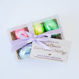 A gift box of four Dark Chocolate Salted Caramel Eggs, foil-wrapped with a lavender ribbon from Jessica Foster Confections.