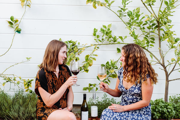 2 women sitting outside dinking a glass of wine