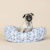 A small pug sits upright in the Indigo Vine Canvas Small Round Cuddler Pet Bed against a beige background.