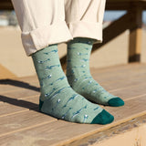 Person in cream pants wearing Socks that Protect Whales on a sunlit wooden boardwalk