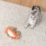 Gray tabby kitten on white rug with Very Crabtivating Earth Friendly Cat Toy, beside an orange crab plush.