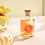Bottle of Brightland Champagne Vinegar on a table with a yellow flower and decorative plate.