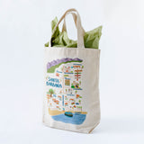 Welcome gift bag with a colorful illustration of Santa Barbara filled with local snacks on a white background