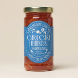 A jar of Cara Cara & Hibiscus Marmalade with a blue label from Marmalade Grove, Ojai, California.
