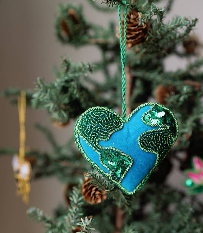 Heart-shaped blue and green ornament hanging on a Christmas tree.