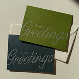 An olive green and a dark blue Season’s Greetings Note Card with silver foil text, each including a natural envelope.