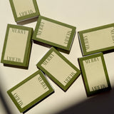 Several Matchbox Merry Merry boxes with green borders scattered on a surface, each printed with MERRY on every side.