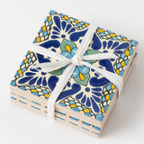 Laila Ceramic Tile Coaster Set: four vibrant floral tiles in blue, yellow, & green, tied with a white ribbon.
