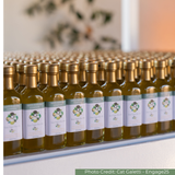 Row of small Santa Barbara olive oil bottles at an event with gold caps.