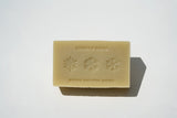 A beige organic bar soap, Christmas Fir Soap, with "JUNIPER RIDGE" and "BRING NATURE HOME" embossed above and below snowflakes.