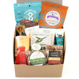 The Classic California Welcome Gift is a self-care box featuring almonds, caramel, gummy bears, CA snacks, crackers, towelettes, sunscreen, paprika snacks, and a chocolate bar—all neatly packed in a brown box.