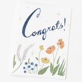 The Congrats Botanical Note Card features "Congrats!" in blue cursive, with pastel flowers and greenery on white recycled paper—an eco-friendly greeting card perfect for celebrating special moments.