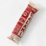 Foustman's Pork Fennel & Pepper Salami—uncured, with fennel and pepper, comes wrapped in cream and red paper featuring bold text and a vintage design on a white background.
