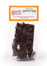 A clear bag of Ginger Walnut Dark Chocolate Bark by Wooden Table Baking Co., handmade in Oakland, CA by an LGBTQ-led bakery, with visible walnut pieces and an orange-and-white label at the top.