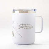 The Golden State California Insulated Camp Mug is a white mug with a handle and clear lid, gold “Golden State California est. 1850” text, and floral design—ideal for California adventures.
