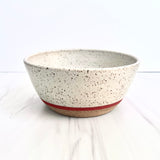 The Handmade Klapp Ceramic Planter features a speckled off-white glaze, natural clay base, and thin red stripe. Locally crafted by Atlas Klapp Ceramics in Santa Barbara, it’s shown on a light-colored surface.