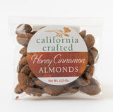 A clear bag of Honey & Cinnamon California Almonds - 2.5 oz reveals sweet California almonds inside. The circular label displays green and orange text, making this snack a perfect sweet treat.
