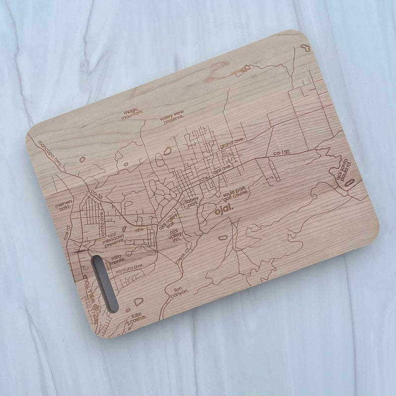 Pictured is a rectangular wood cutting board with the map of Ojai California engraved on it.
