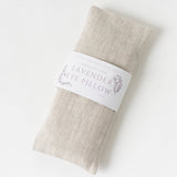 The Lavender Linen Eye Pillow, beige with a white label, is shown on a white background.