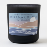 A black jar labeled Miramar Santa Barbara Spa Tote—perfect as a gift, with a pastel beach and 7oz Soy Candle text.