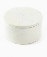 The Natural Soapstone Round Treasure Box is a hand-carved, round white box with a matching lid and subtle gray veining. Crafted by Kenyan artisans, it's smooth and elegant, shown closed against a white background.