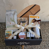 The Top Tier Custom Gift features snacks, Cheese Coins, cookies, and oils in a ribbon-tied box on a wooden board.