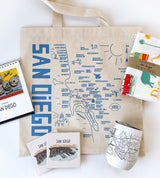 The San Diego Map Tote gift set includes a blue map tote bag, city map travel mug, calendar, tea towel, and two illustrated coasters—a perfect collection for San Diego enthusiasts.