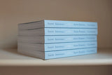 A stack of five light blue Santa Barbara Guide Books sits on a beige shelf.