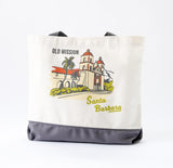 The Santa Barbara Mission Canvas Tote is a screen-printed bag with gray handles and bottom, featuring the iconic Old Mission, palm trees, and “Old Mission Santa Barbara” text. Proudly made in the USA.