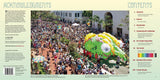 A lively crowd celebrates the Santa Barbara Summer Solstice as a vibrant, dragon-like float parades past historic buildings and palm trees beneath a sunny, clear sky.