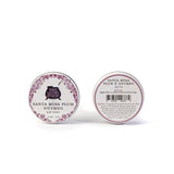 Two tins of Santa Rosa Plum & Nutmeg Lip Tint—one labeled, one showing ingredients—made with all-natural extracts.