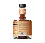 The Tandem Smoky & Oaky Non-Alcoholic Cocktail comes in a glass bottle with a brown label and black cap. The dark liquid inside is ideal for vegan cocktails. Nutrition facts, ingredients, and a barcode appear on the back. Set on a white background.