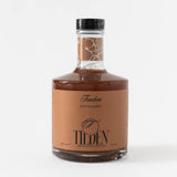 A glass bottle labeled “Tandem Smoky & Oaky” by Tilden Non-Alcoholic Cocktails, filled with brown liquid. This vegan, ready-to-serve drink has a tan label with black and white text and is topped with a black cap.