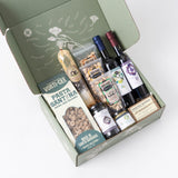 A Taste of Santa Barbara Gift Box with wine, olive oil, breadsticks, pasta, cookies, and a loaf on white background.