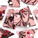 Valentine’s Day Strawberry Cheesecake Chocolate Bark features swirled pink and berry chocolate, topped with red, white, and pink candy-coated chocolates and heart sprinkles—a festive treat perfect for Valentine’s Day.