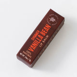 A rectangular maroon box labeled Vanilla Bean Shimmer Lip Balm with white and orange text, displayed on a white background.