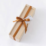 The Wood Wine Gift Box with Ribbon is a rectangular light wooden box tied with a shiny brown ribbon and an attached small card, displayed on a white background.