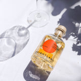 Citrus Champagne Vinegar bottle on a white tablecloth, next to a wine glass and soft shadows.
