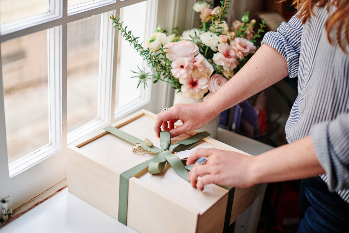 Santa Barbara Company Gift Box being tied up with green ribbon.