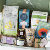 Assorted gourmet food items in a box with visible branding and packaging.