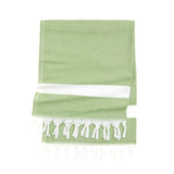A green Turkish towel with white patterns and fringe, shown with a custom logo band for beach & bath towels.