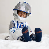 Smiling child in an astronaut costume and helmet wearing navy space socks