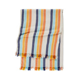 A folded striped textile with fringed edges, featuring vertical bands of cream, navy, orange, and light blue on a white background.