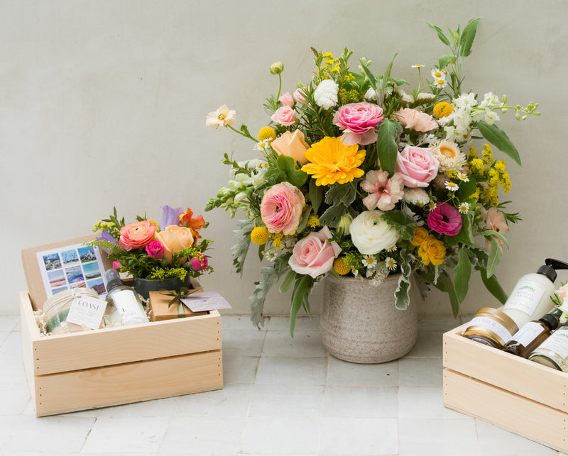 mothers day flower arrangement and gift basket on a table