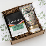 Handlebar Coffee Break Gift Box with coffee beans, organic pistachios, and a gold soy candle on crinkle paper.
