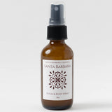 Brown bottle labeled Santa Barbara Room & Body Mist with black cap, clean fragrance travel spray on white background.