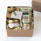 Gift box with Santa Barbara candle, nuts, and chocolate on a white background
