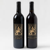 Two bottles of Theopolis Vineyards red wine, the 2021 Estate Grown Petite Sirah and Theo-Patra's Cuvée Cerise, each labeled with a gold Egyptian-style figure on a black background.