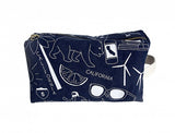 The Blue California Dopp Kit is a navy canvas pouch with white illustrations—bear, sunglasses, wind turbines, highway sign, and smartphone. It features a zippered top, white end strap, and is made of cotton in the USA.