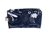 The Blue California Dopp Kit is a navy canvas pouch with white illustrations and “California” text, plus a beige side handle. Made in the USA from cotton—ideal for stylish, convenient on-the-go storage.